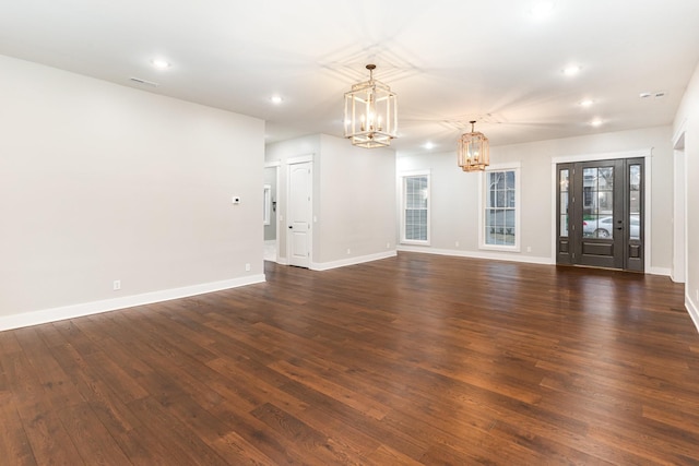 unfurnished living room featuring an inviting chandelier and dark hardwood / wood-style flooring