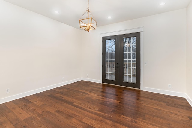 empty room featuring dark wood-type flooring, a notable chandelier, and french doors