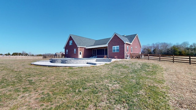 back of house with a yard and a rural view