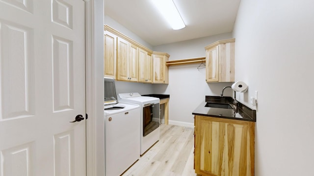 laundry area featuring light hardwood / wood-style floors, sink, washing machine and clothes dryer, and cabinets