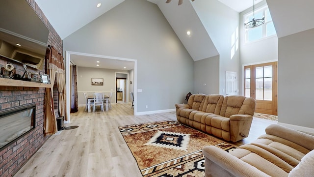 living room with high vaulted ceiling, ceiling fan, a fireplace, and light hardwood / wood-style flooring