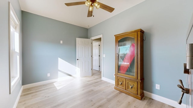 spare room featuring light wood-type flooring, ceiling fan, and plenty of natural light