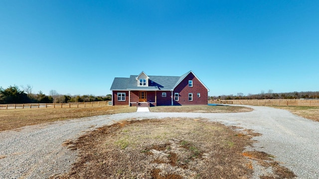 cape cod home featuring a rural view and a porch