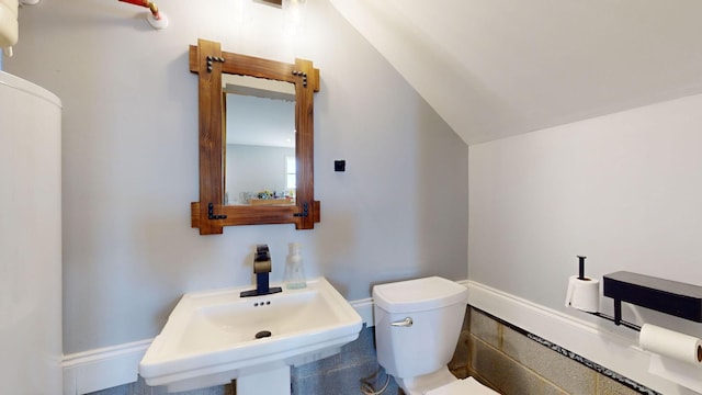 bathroom featuring toilet, vaulted ceiling, and sink