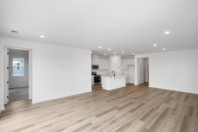 unfurnished living room featuring sink and light hardwood / wood-style flooring