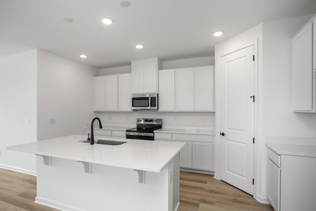 kitchen featuring sink, white cabinetry, stainless steel appliances, and an island with sink