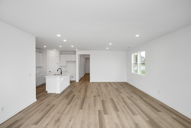 unfurnished living room with sink and light hardwood / wood-style flooring