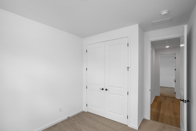 unfurnished bedroom featuring light carpet and a closet