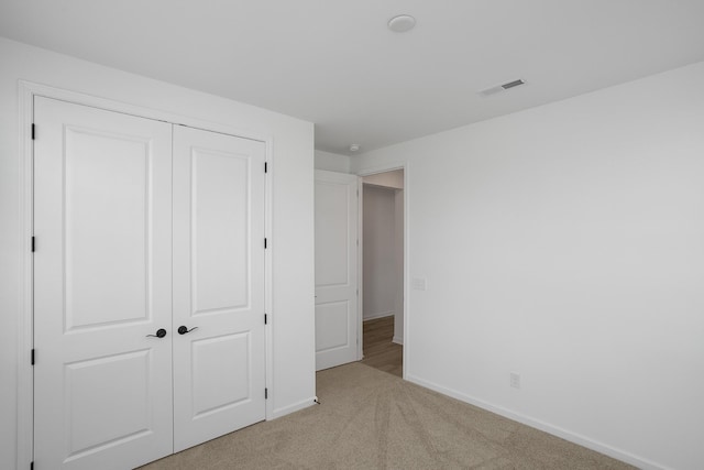 unfurnished bedroom with light carpet and a closet