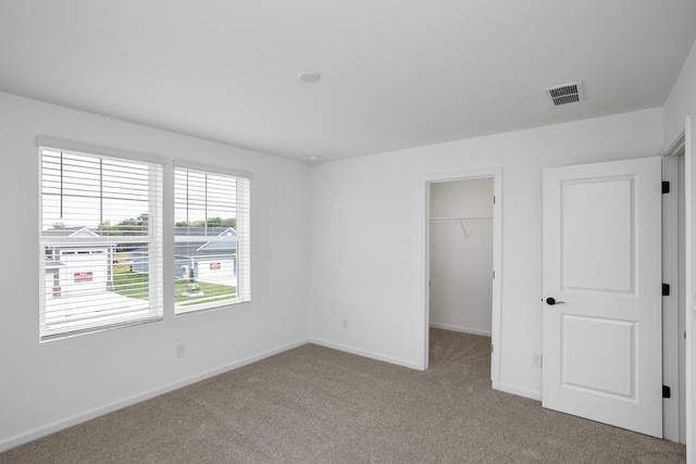 unfurnished bedroom featuring a spacious closet, light colored carpet, and a closet