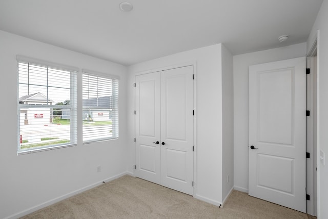 unfurnished bedroom with light carpet and a closet