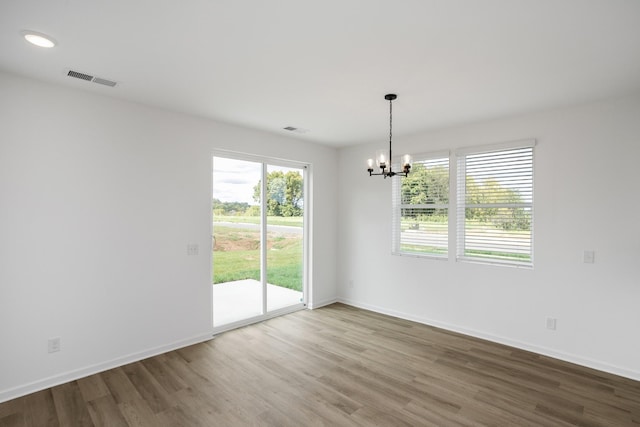 unfurnished room with hardwood / wood-style flooring and an inviting chandelier