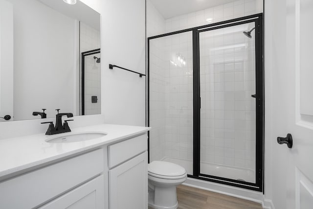 bathroom featuring hardwood / wood-style flooring, vanity, toilet, and a shower with door