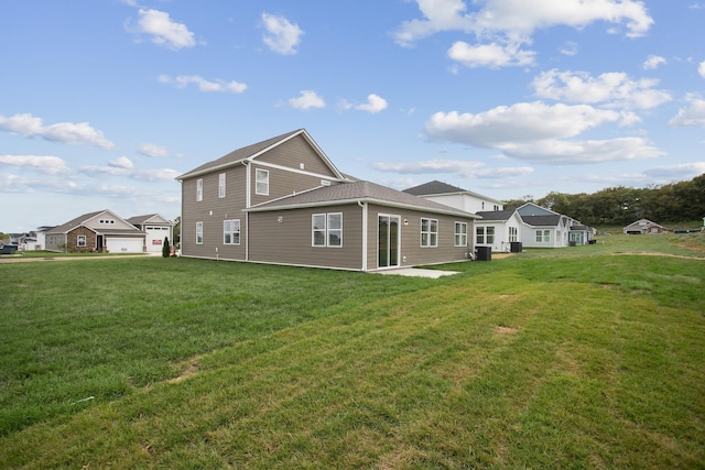 back of house featuring a garage and a lawn