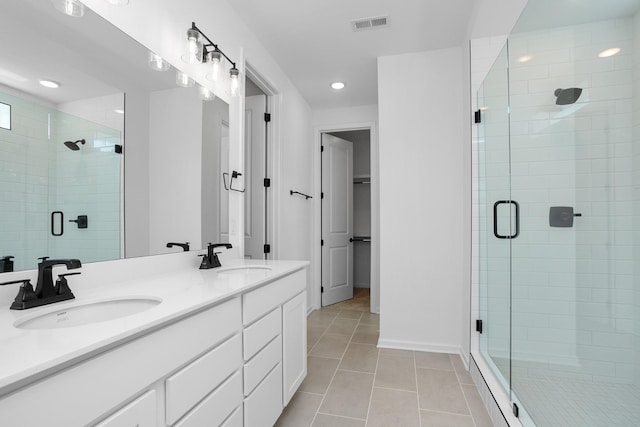 bathroom with walk in shower, vanity, and tile patterned flooring