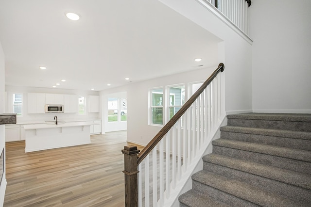 staircase with hardwood / wood-style flooring and sink