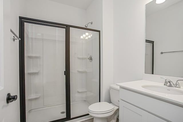 bathroom with toilet, vanity, and a shower with door