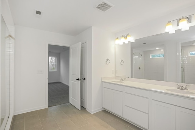 bathroom featuring a shower with shower door, vanity, and tile patterned flooring