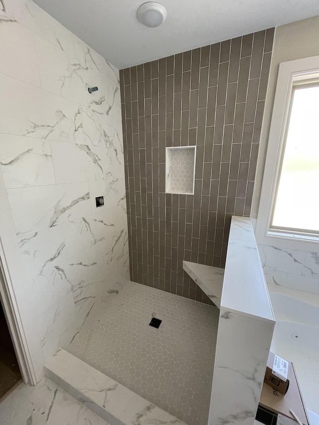 bathroom with a tile shower and marble finish floor