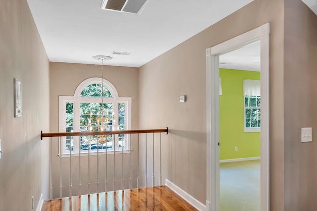 corridor featuring hardwood / wood-style floors and an inviting chandelier