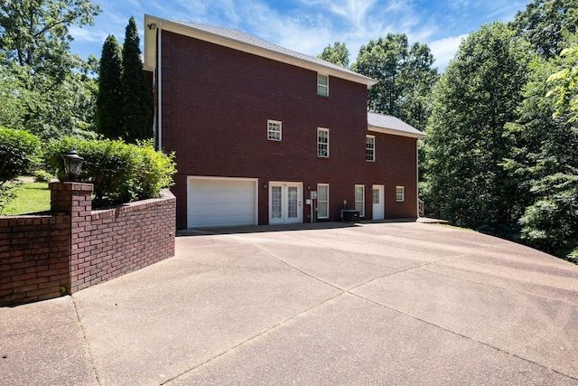 view of home's exterior with cooling unit, french doors, and a garage