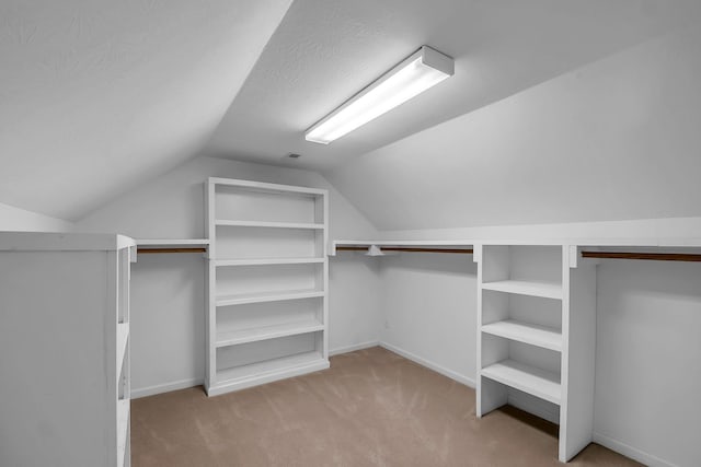 walk in closet featuring lofted ceiling and light colored carpet