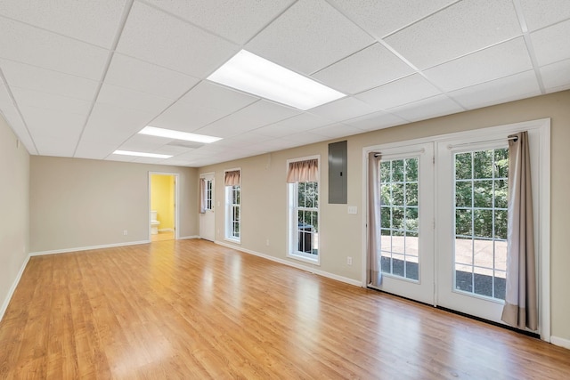 empty room featuring a drop ceiling, light hardwood / wood-style floors, and electric panel