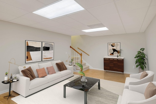 living room with a paneled ceiling and light hardwood / wood-style floors