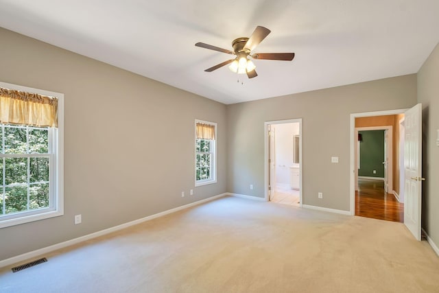 unfurnished bedroom featuring ceiling fan, light colored carpet, and connected bathroom