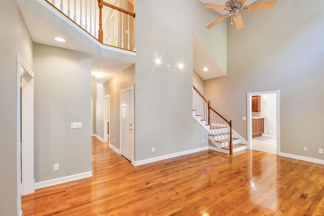 interior space with ceiling fan, light wood-type flooring, and a towering ceiling