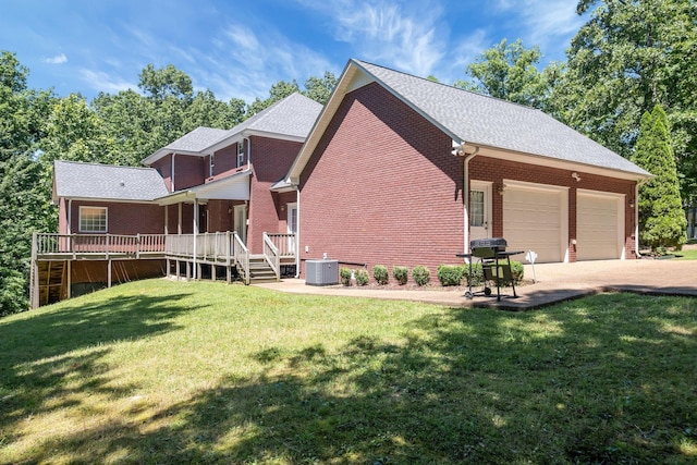 rear view of property featuring central air condition unit, a yard, and a garage