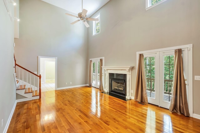 unfurnished living room featuring ceiling fan, light hardwood / wood-style floors, and a high ceiling