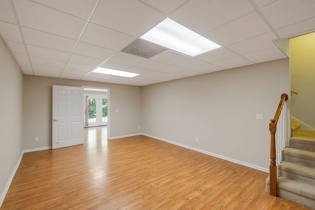 empty room with light hardwood / wood-style flooring, a drop ceiling, and french doors