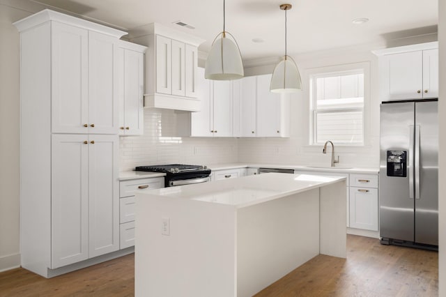 kitchen featuring pendant lighting, white cabinets, a center island, stainless steel appliances, and light hardwood / wood-style flooring