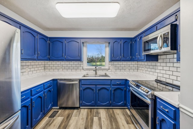 kitchen featuring a textured ceiling, stainless steel appliances, light hardwood / wood-style floors, and sink