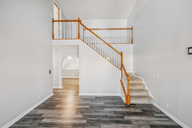 stairs with a high ceiling and wood-type flooring