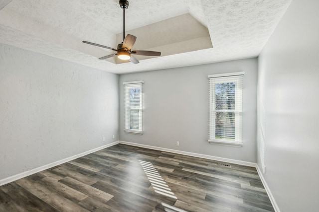 spare room featuring ceiling fan, a textured ceiling, dark hardwood / wood-style floors, and a raised ceiling