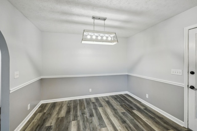 unfurnished dining area with a textured ceiling and dark hardwood / wood-style flooring