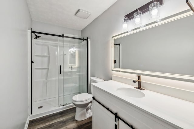 bathroom featuring toilet, vanity, a shower with shower door, and hardwood / wood-style flooring