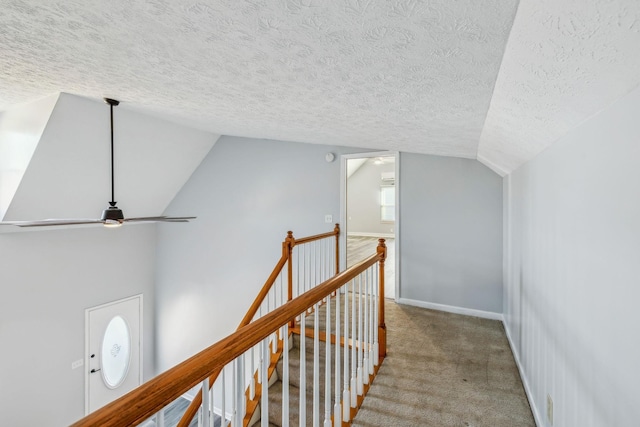 hall with vaulted ceiling, a textured ceiling, and light colored carpet