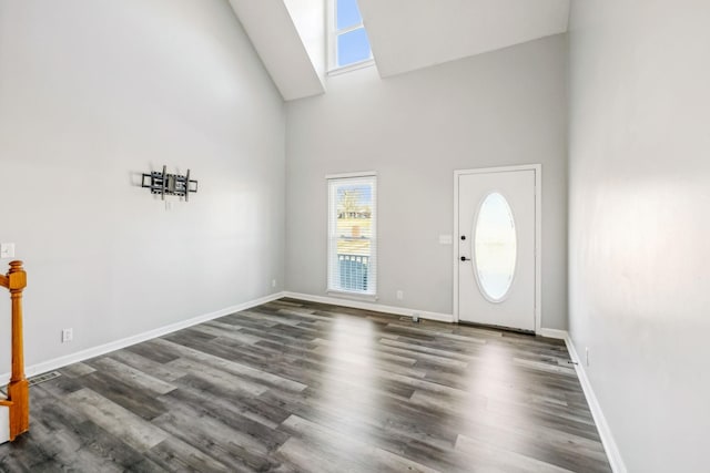 entrance foyer with dark wood-type flooring and a towering ceiling