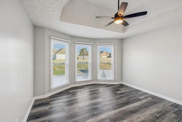 spare room featuring ceiling fan, dark hardwood / wood-style floors, a tray ceiling, and a textured ceiling