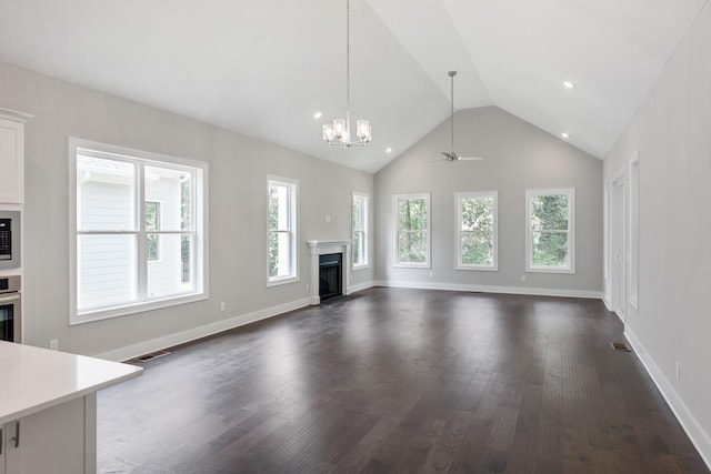 unfurnished living room with vaulted ceiling, dark wood-type flooring, and ceiling fan with notable chandelier