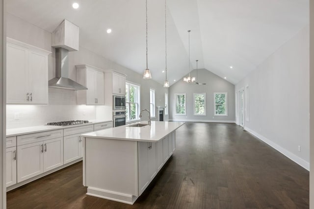 kitchen with decorative light fixtures, a center island with sink, sink, appliances with stainless steel finishes, and white cabinets