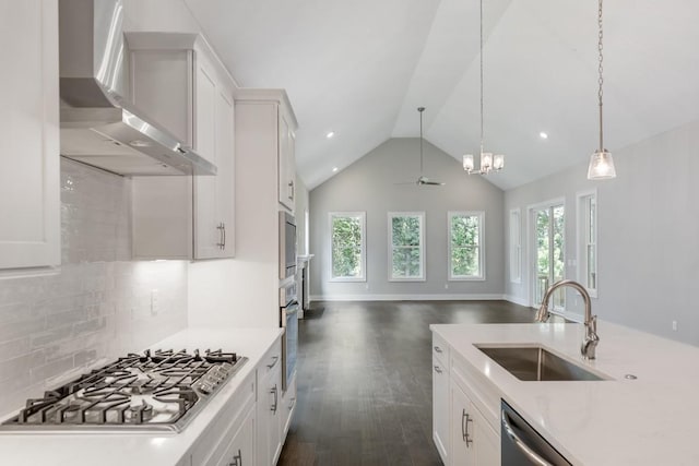 kitchen featuring ceiling fan, stainless steel appliances, wall chimney exhaust hood, white cabinets, and sink