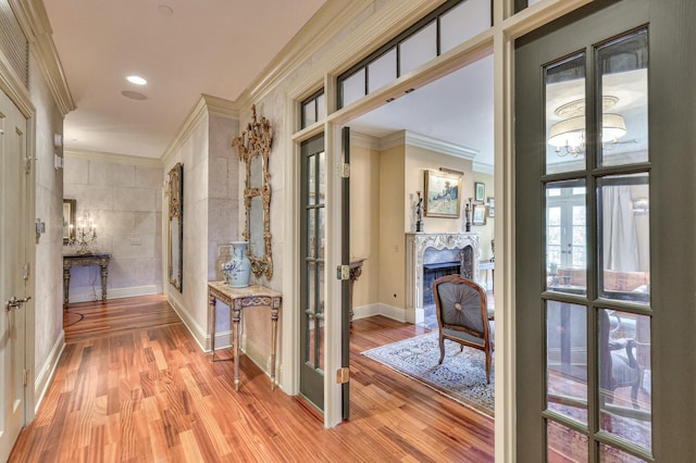 corridor with crown molding, french doors, and light wood-type flooring