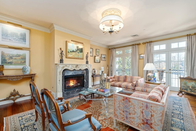 living room with french doors, a fireplace, crown molding, and hardwood / wood-style flooring