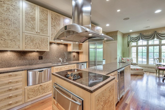 kitchen with a kitchen island, island exhaust hood, stainless steel appliances, light hardwood / wood-style floors, and sink