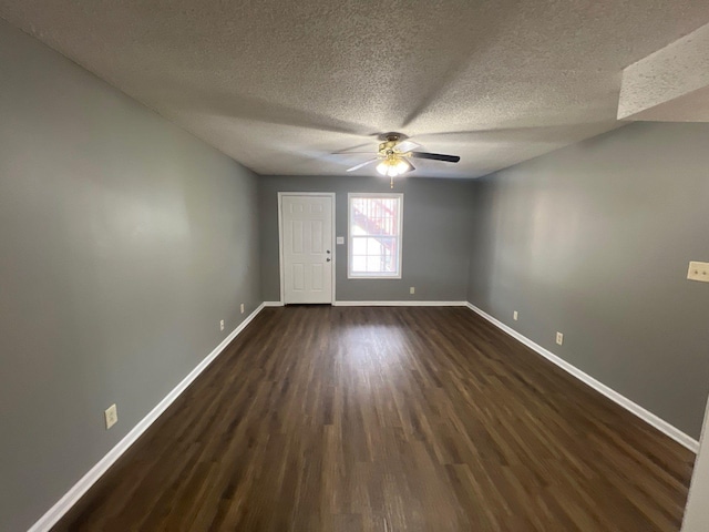 empty room with a textured ceiling, ceiling fan, and dark hardwood / wood-style flooring