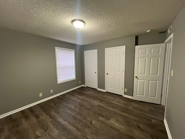 unfurnished bedroom with a textured ceiling and dark wood-type flooring